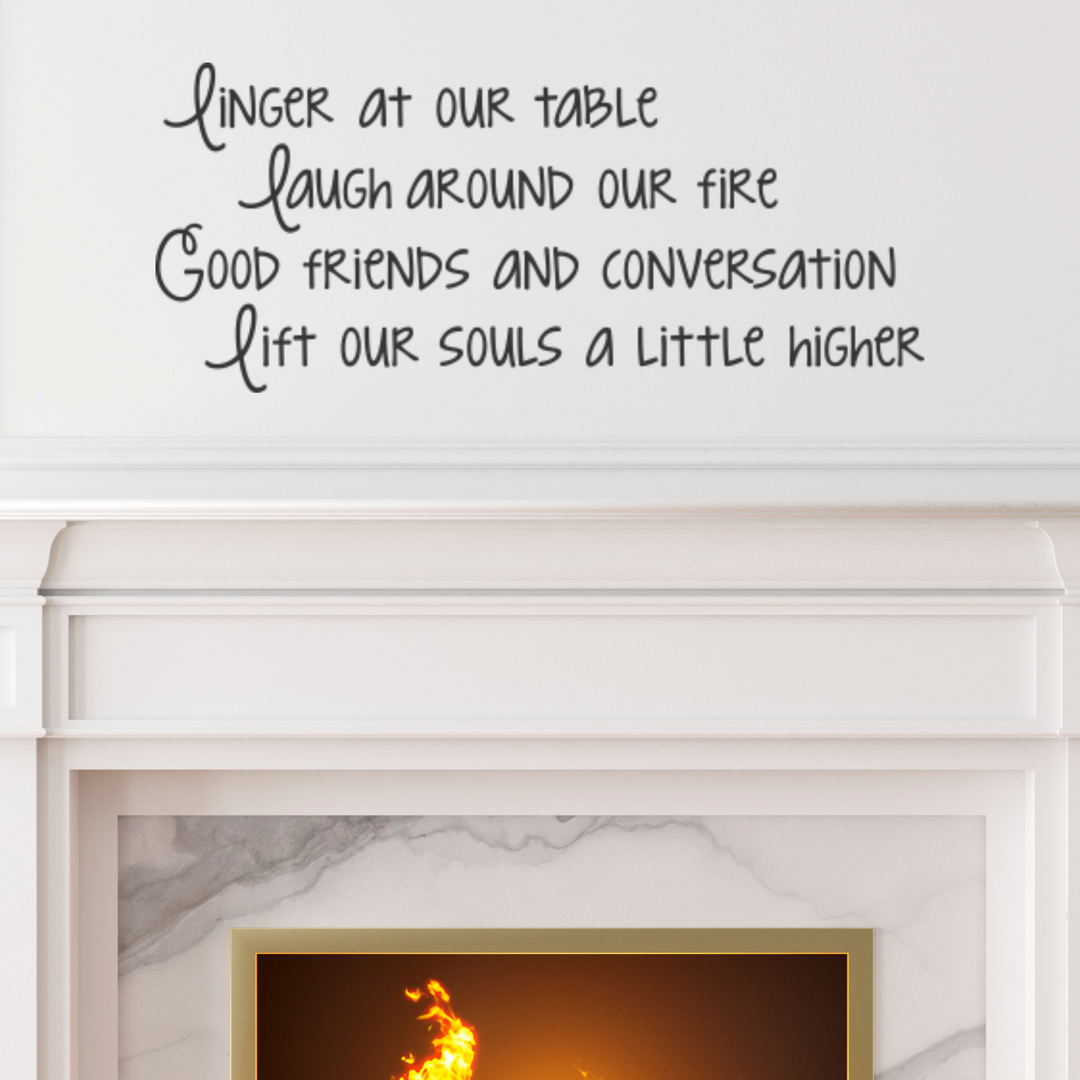 Elegant fireplace mantle with a black custom vinyl lettering decal 'Linger at our table laugh around our fire Good friends and conversation lift our souls a little higher' on the wall above. Ideal living room wall stickers or fireplace wall quotes to enhance a cozy, conversational space with inspirational vinyl decals.