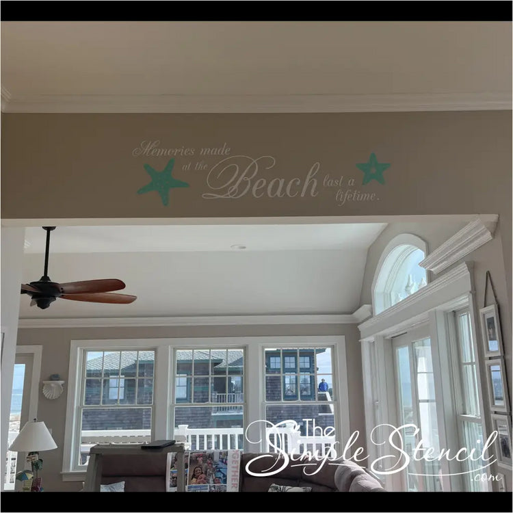A charming wall decal adorns the sun-drenched interior of a beachfront home, its message "Memories made at the beach last a lifetime" resonating with the picturesque ocean view beyond. Two playful starfish graphics, their delicate forms reminiscent of seaside treasures, complement the heartfelt sentiment, capturing the essence of enduring coastal memories.
