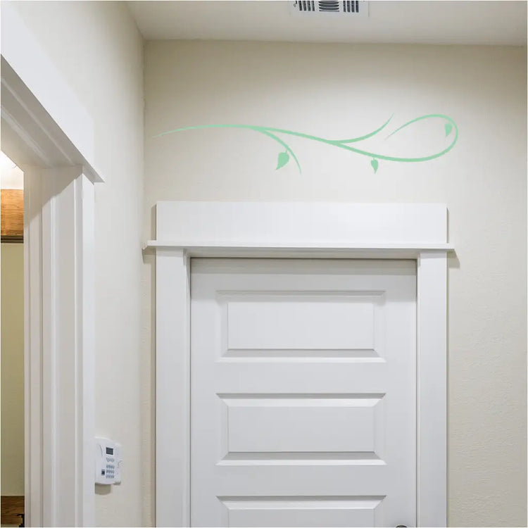 Simple branch flourish decal applied to a clean white wall, showcasing its elegant curve.