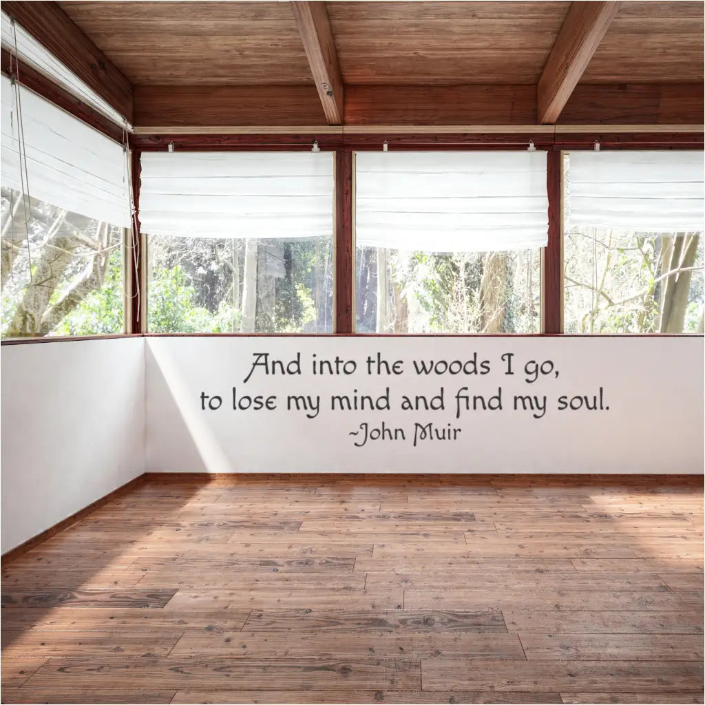John Muir quote "And into the woods I go, to lose my mind and find mysoul" displayed as a custom vinyl wall decal in a cozy mountain lodge living area.