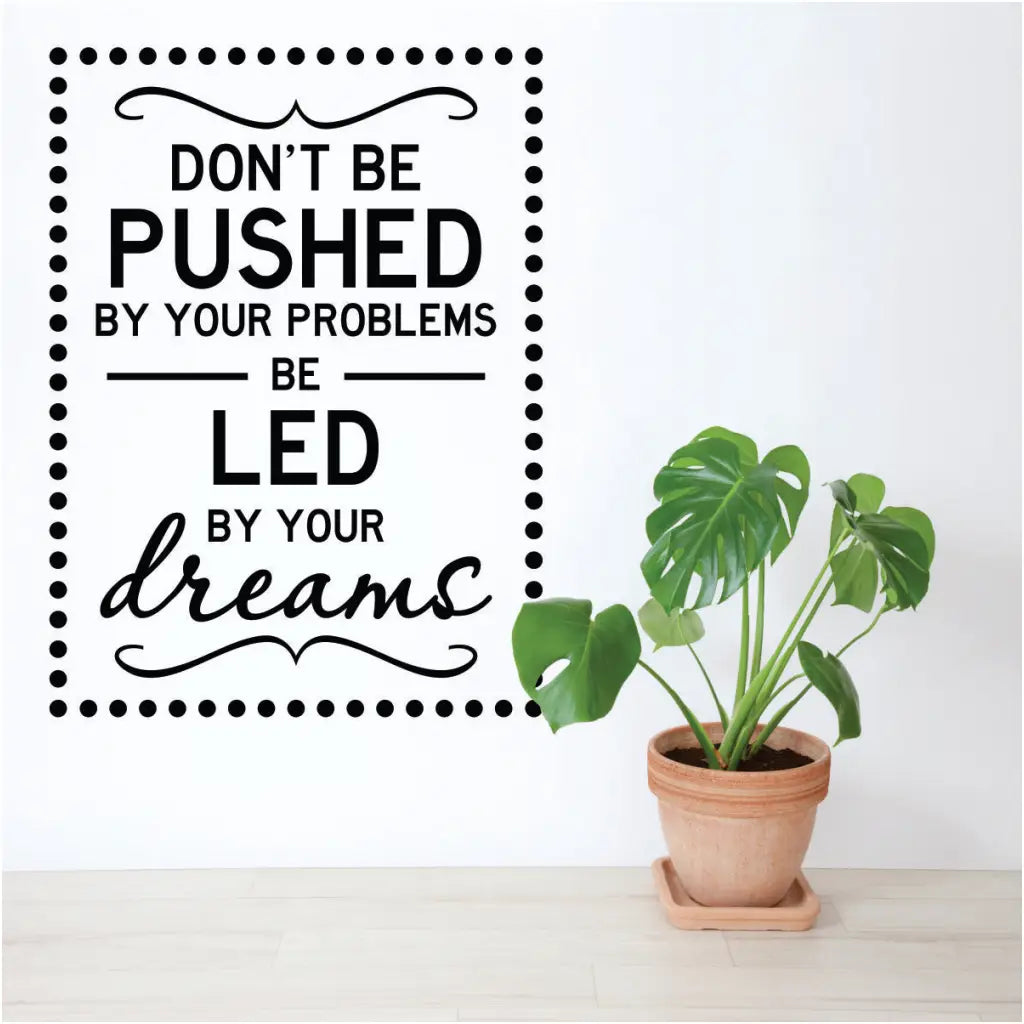 A cute vinyl wall decal for an office or study area that reads: Don't be pushed by your problems, be led by your dreams. Surrounded by polka dot frame.