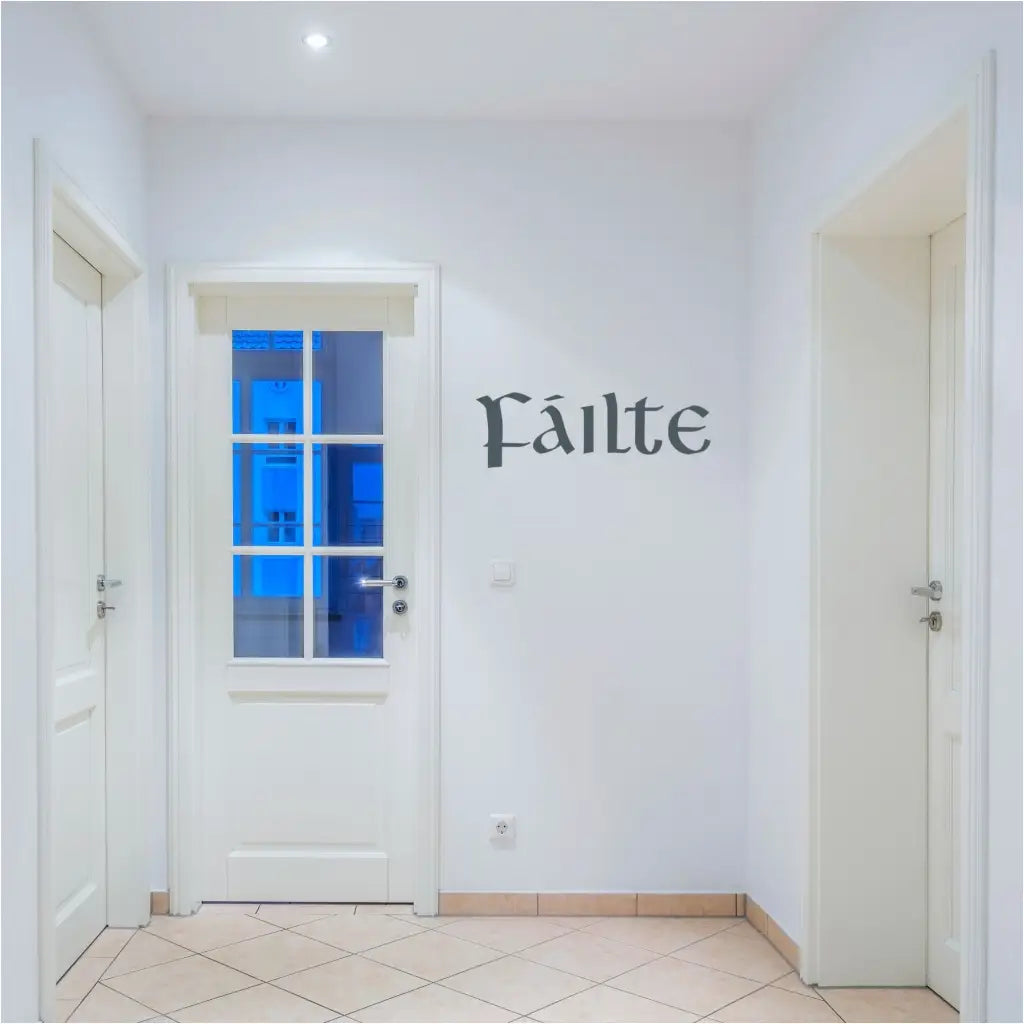 A close-up photo of the "Fáilte" wall decal in a green vinyl applied to a white painted door. The word is written in a bold, Celtic script font.