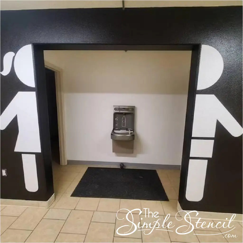 Customer supplied photo of boy and girl restroom sign decals installed on walls leading to restrooms to help students and non english reading visitors find restrooms with ease. By The Simple Stencil