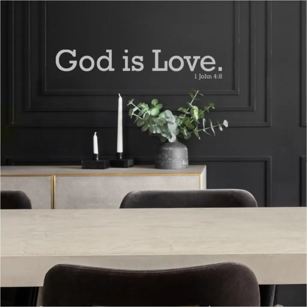 Close-up of a white "God is Love 1 John 4:8" wall decal applied to a dark gray wall in a modern church hall