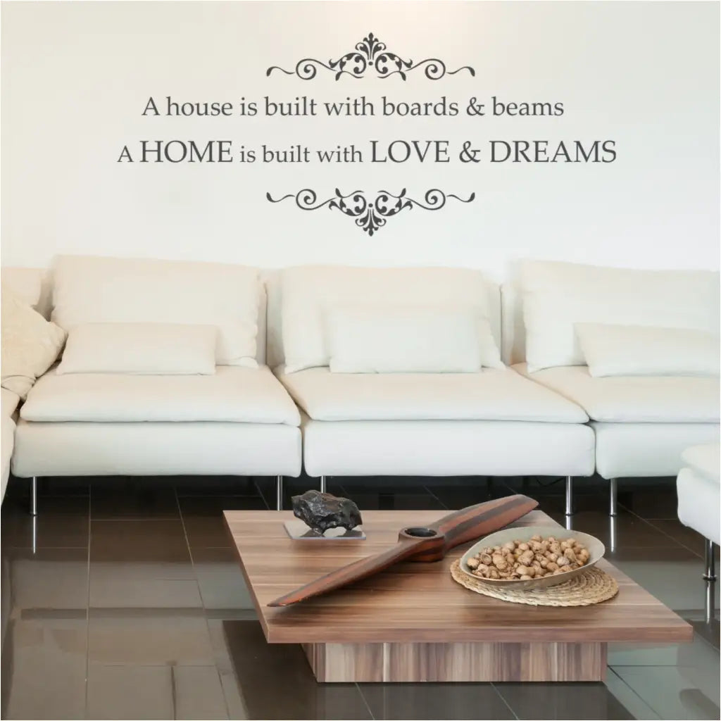 A house is built with boards and beams. A home is built with love and dreams. A vinyl wall decal by The Simple Stencil includes flourish scrolls top and bottom. 
