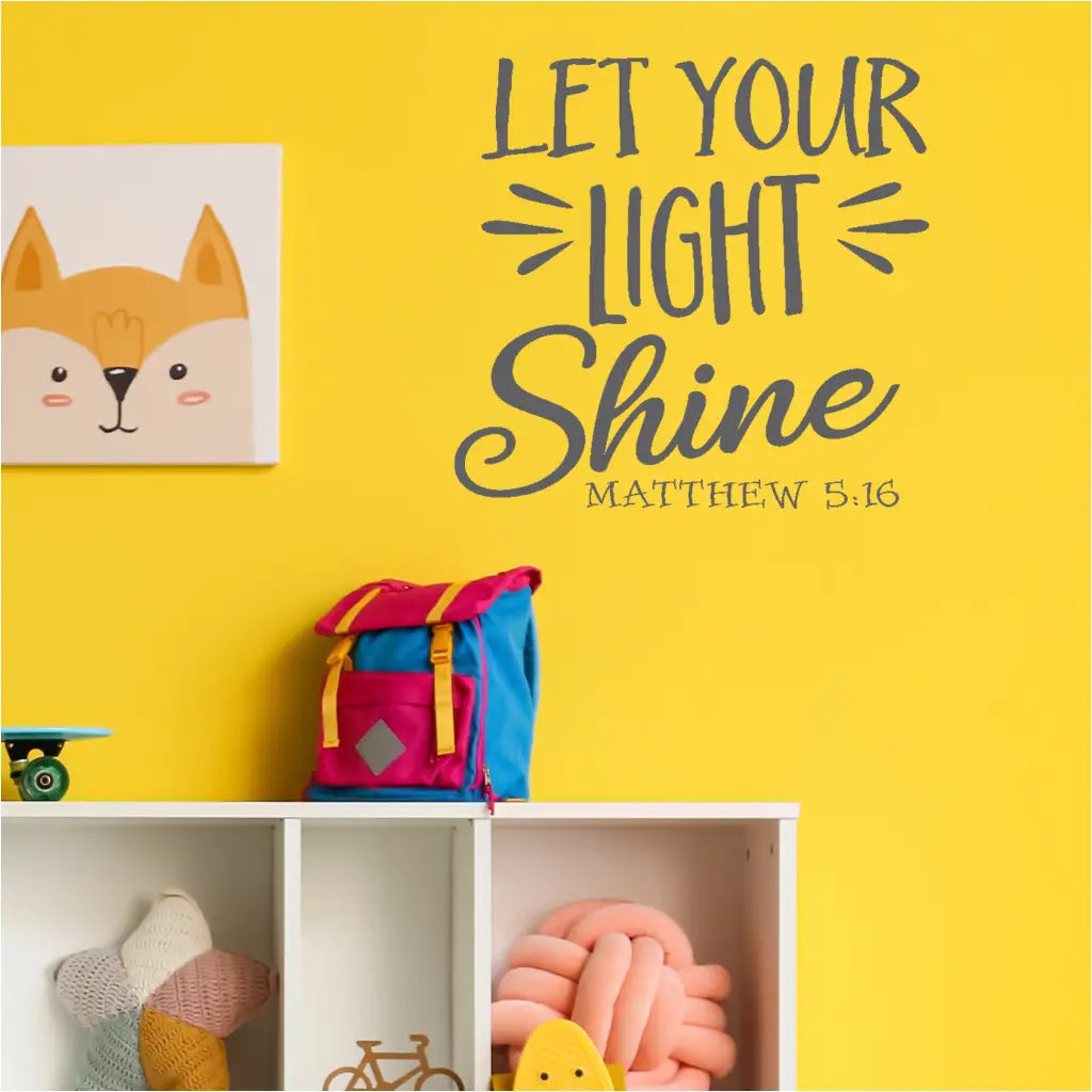 A group of smiling children in a church classroom pointing at a large "Let Your Light Shine" Matthew 5:16 wall decal with a teacher reading a storybook. 