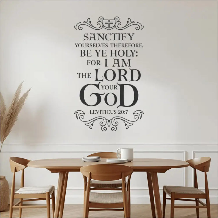 The black Leviticus 20:7 Bible verse wall decal applied to a white wall above a wooden dining table with chairs and a plant in a modern dining room setting.