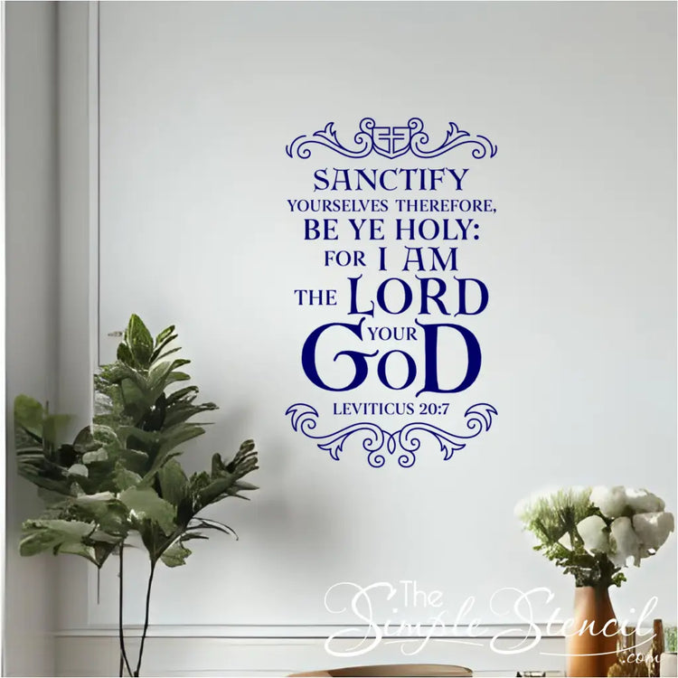 A blue Leviticus 20:7 Bible verse wall decal adorning a white wall in a room with a green plant and white flowers in a vase, suggesting a peaceful home environment.