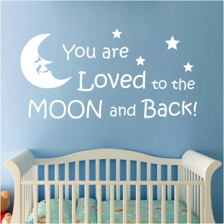 Large "You are loved to the moon and back" vinyl wall decal by The Simple Stencil displayed on blue baby nursery wall over crib.