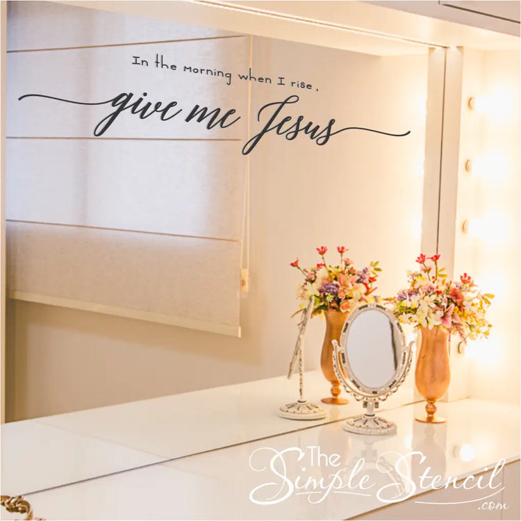 A bright and airy bathroom with the "In the morning when I rise, give me Jesus" wall decal applied to a mirror over a make up table. By The Simple Stencil