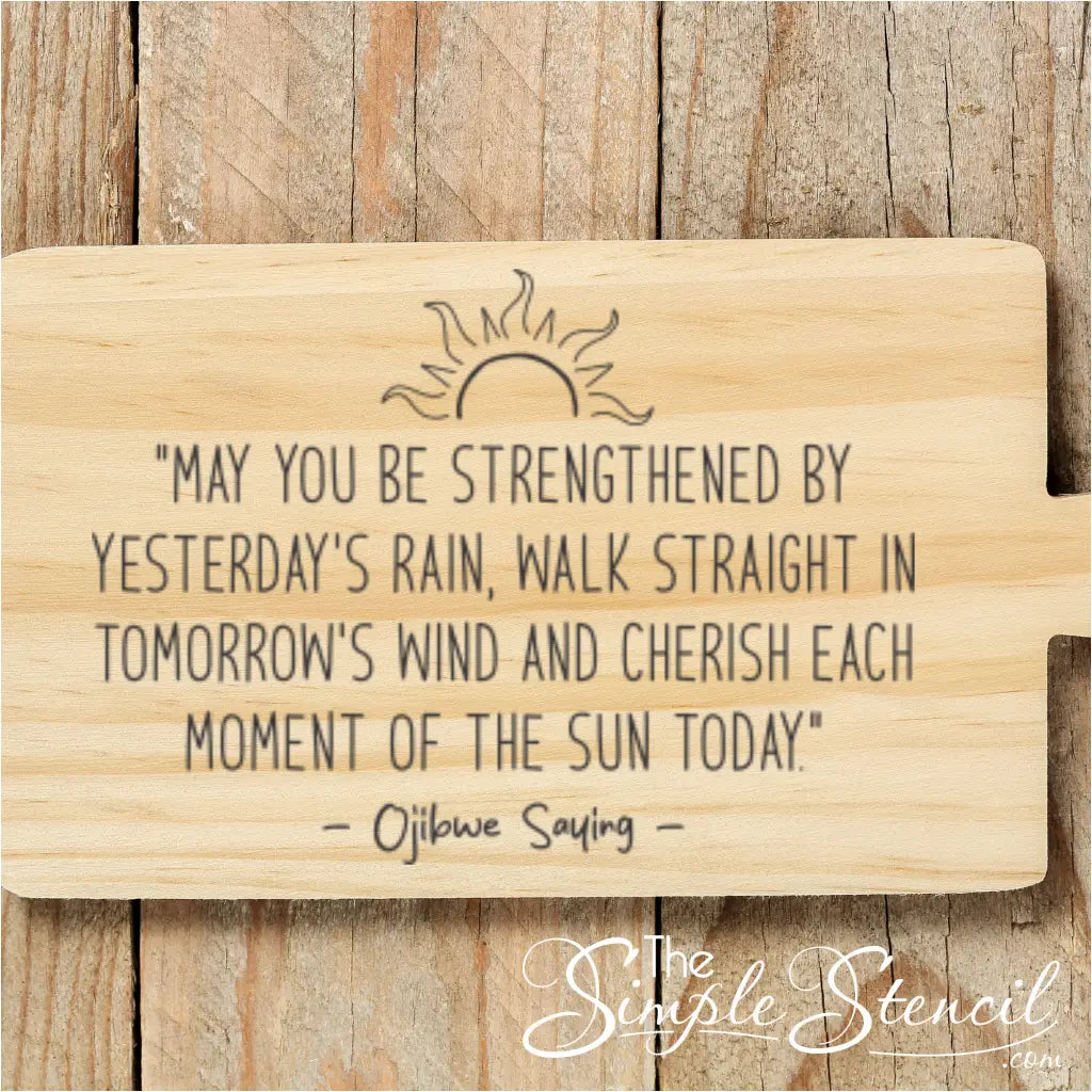 The inspirational Ojibwe saying about rain, wind, and sun displayed on a light wood cutting board against a rustic wood background.