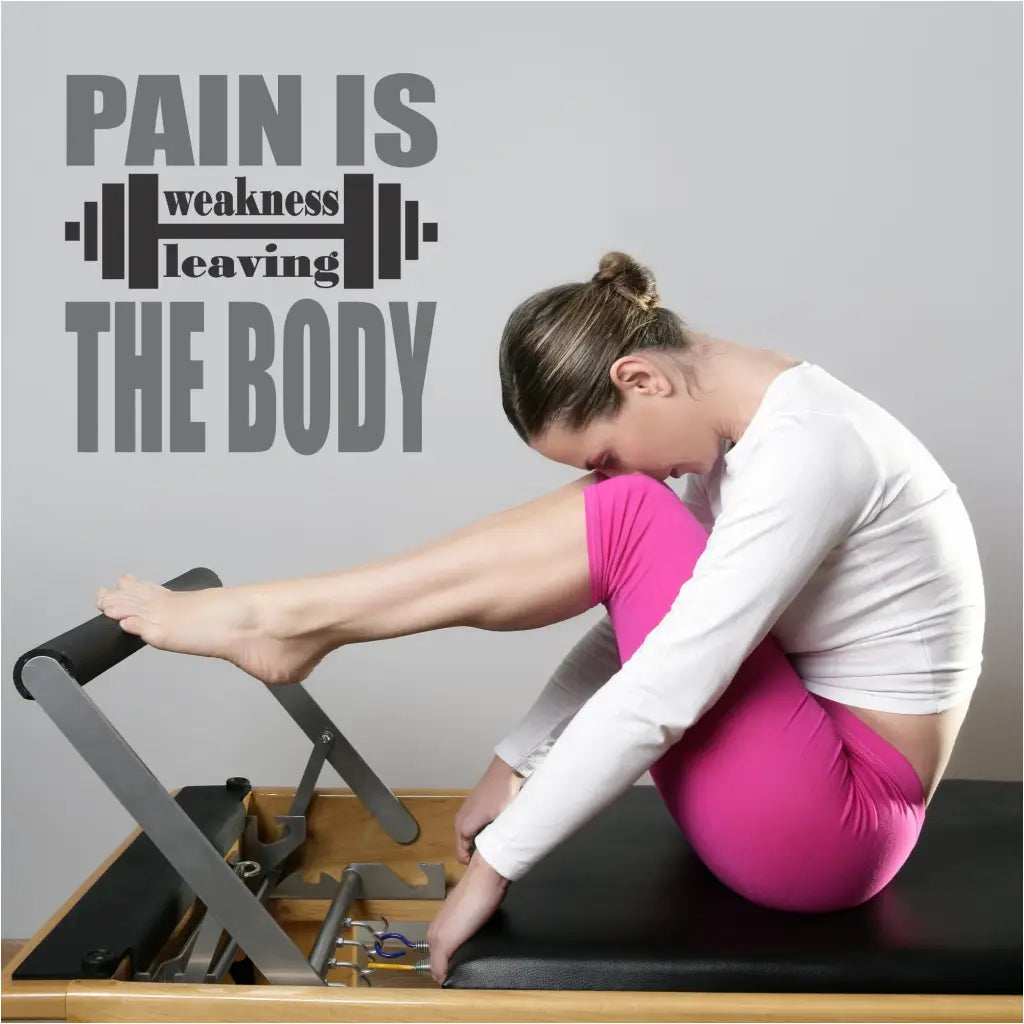 two color wall decal displayed on fitness center wall behind a girl working out on pilates table. 