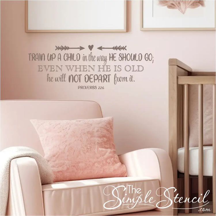 A colorful "Train Up a Child in the Way He Should Go" Proverbs 22:6 vinyl decal displayed on a light pink wall in a church nursery, with baby rocker next to crib and wall quote decal. By The Simple Stencil
