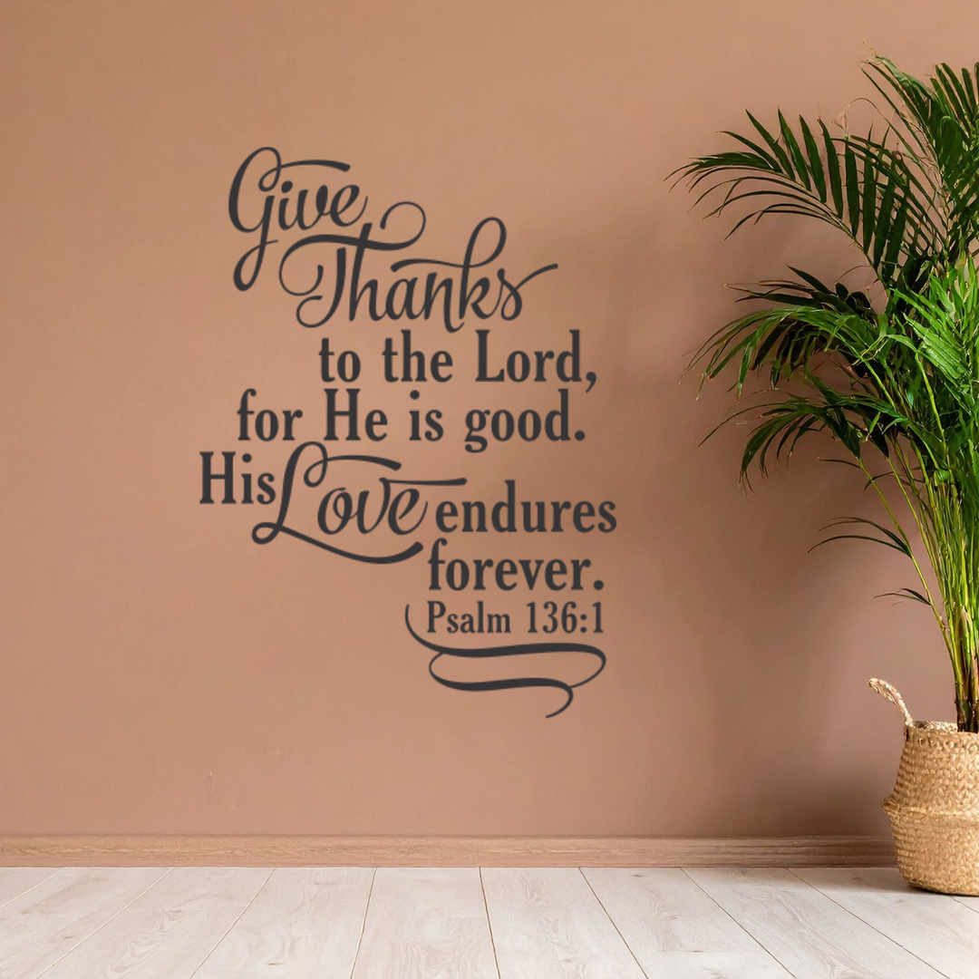 Inspirational Bible verse wall graphic in black, featuring "Give Thanks" beside a large potted plant on a warm, terracotta-colored wall.