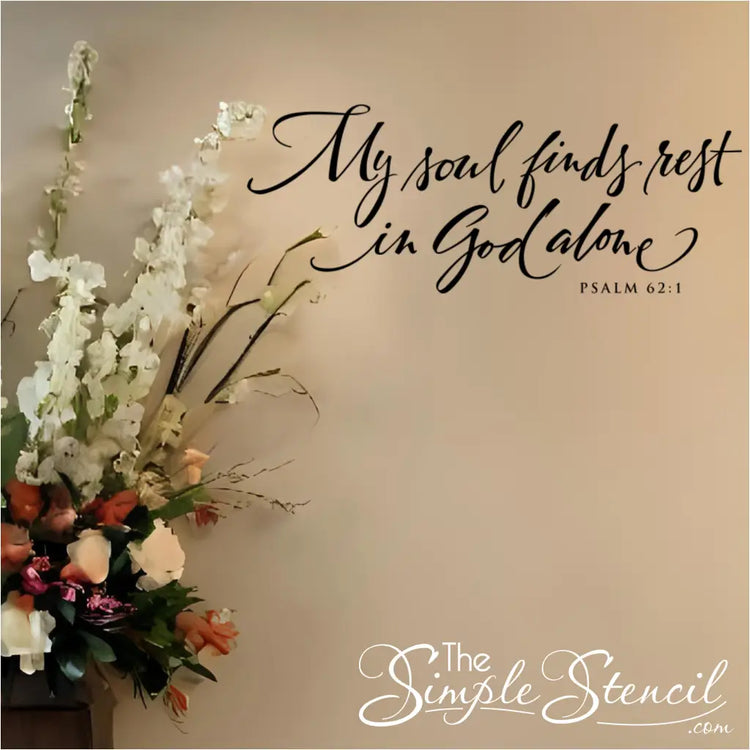 Black scripture decal on a neutral wall next to a large floral arrangement. Elegant wall decor for Christian ministry.