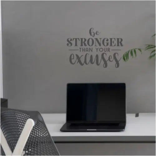A wall quote decal by TheSimpleStencil that reads Be Stronger Than Your Excuses placed over a home office desk.