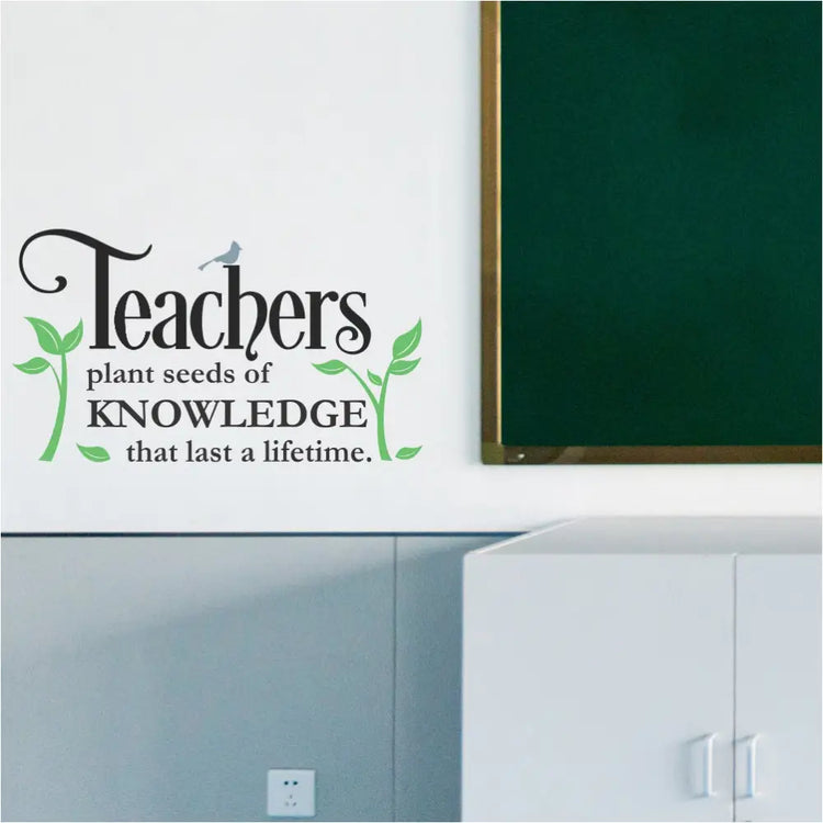 A colorful "Teachers Plant Seeds" inspirational wall decal displayed on a bright teacher's lounge wall with comfortable chairs. The plants, bird, and text are all in different colors to showcase customization options.