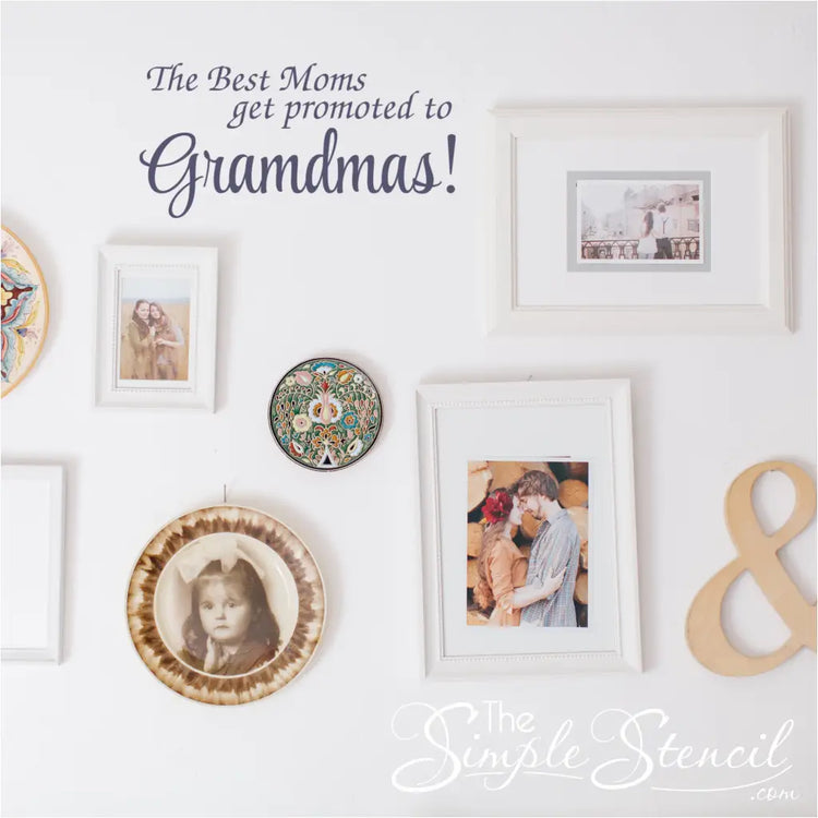 "The Best Moms Get Promoted to Grandmas!" wall decal displayed in a living room  on a wall that displays family pictures and heirlooms 