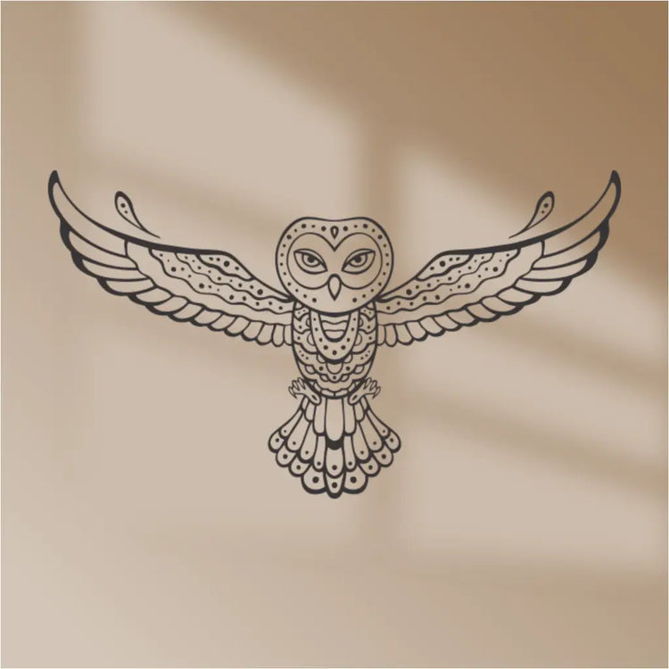 A black tribal owl vinyl wall decal on a beige background, with a shadow from a window casting a pattern on the wall.