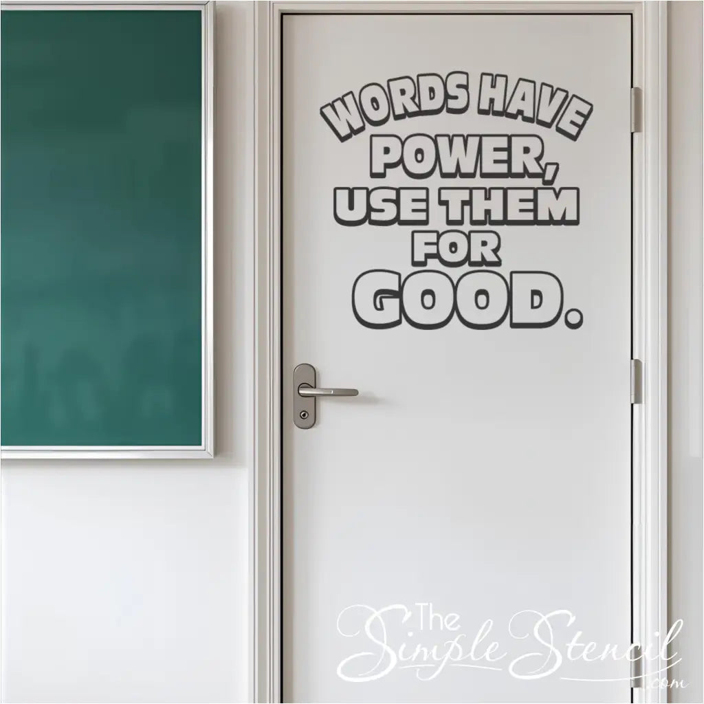 Black outline "Words Have Power, Use Them For Good" vinyl decal on a white classroom door with a silver handle, beside a green chalkboard, illustrating a school hallway kindness message.