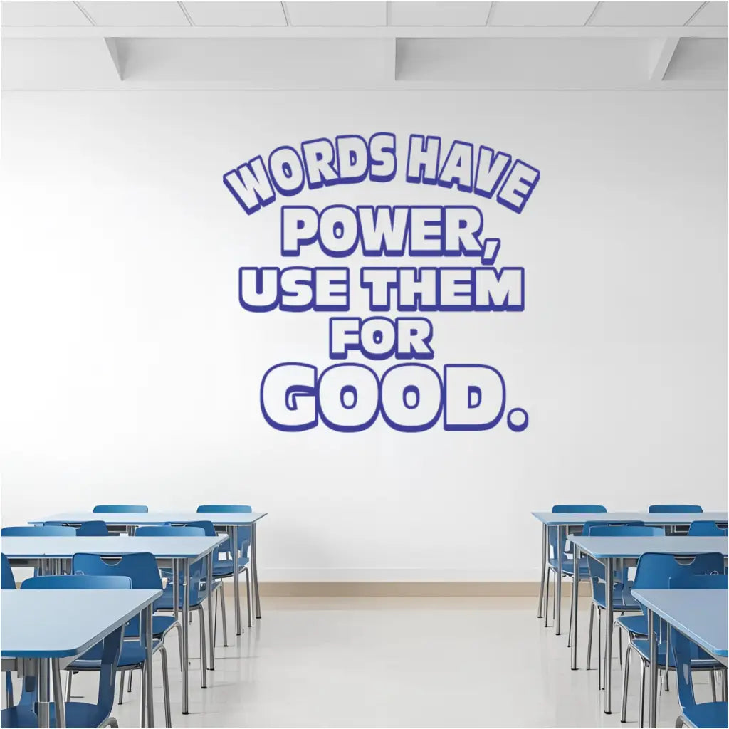 Large blue outline "Words Have Power, Use Them For Good" vinyl wall decal prominently displayed on a white classroom wall above rows of blue student desks and chairs, emphasizing character education in schools.