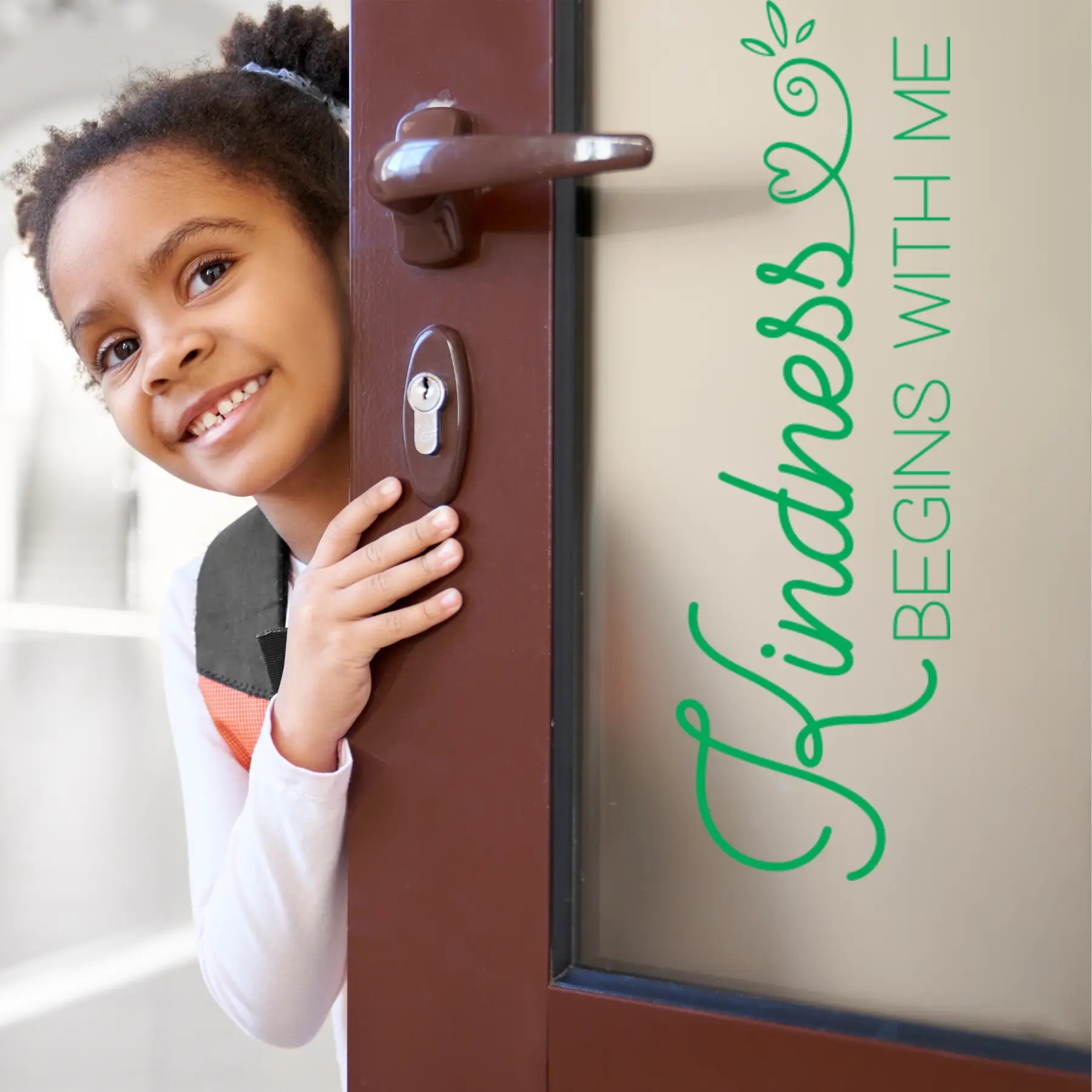 Kindness Decal for Schools: Close-up of a smiling young Black girl peeking through a doorway next to a large vinyl decal that reads, "Kindness BEGINS WITH ME" in bright green script, promoting anti-bullying and positive school culture. 