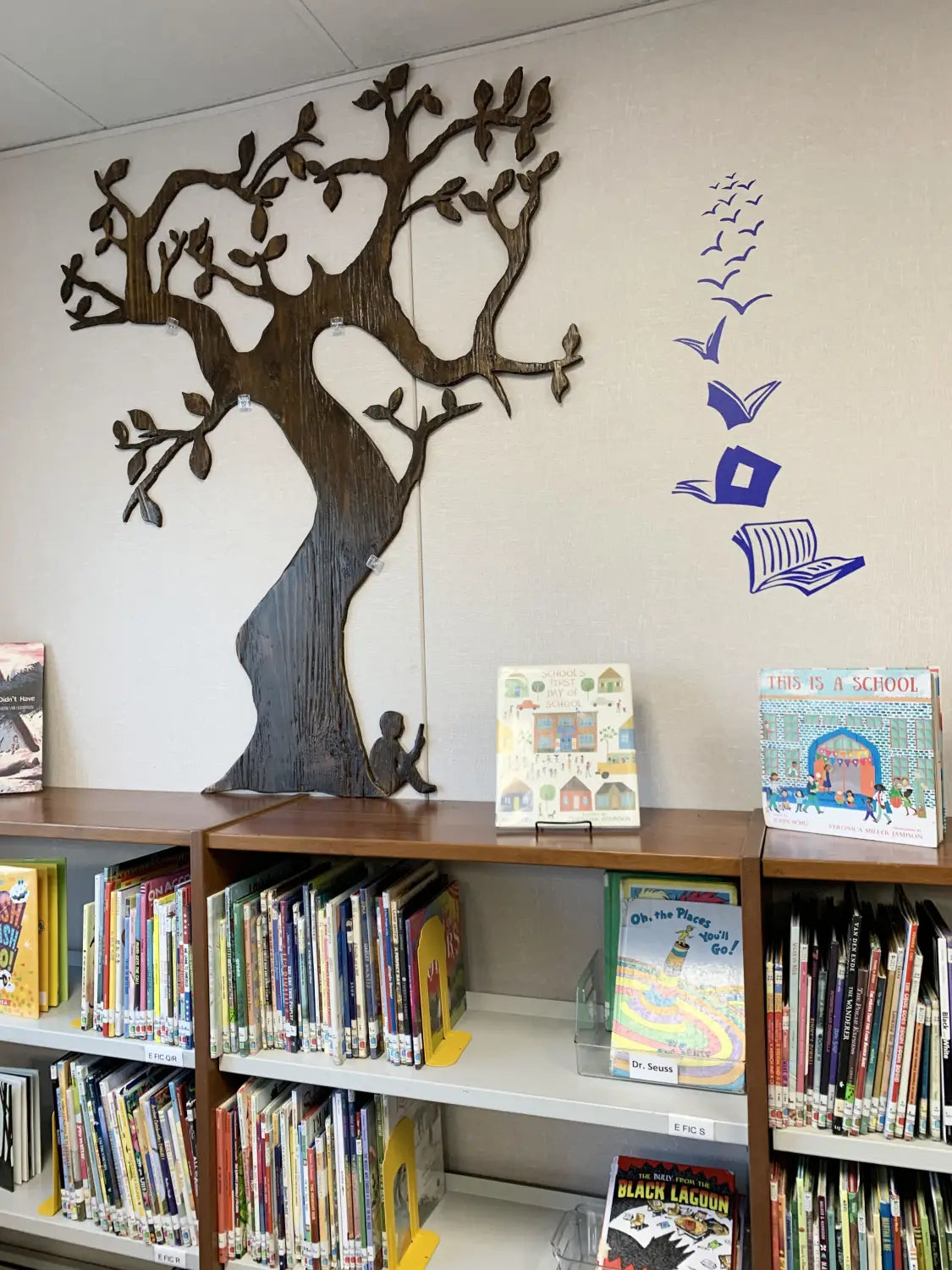 School library wall adorned with a vinyl decal of an open book transforming into flying birds, symbolizing the transformative power of reading.