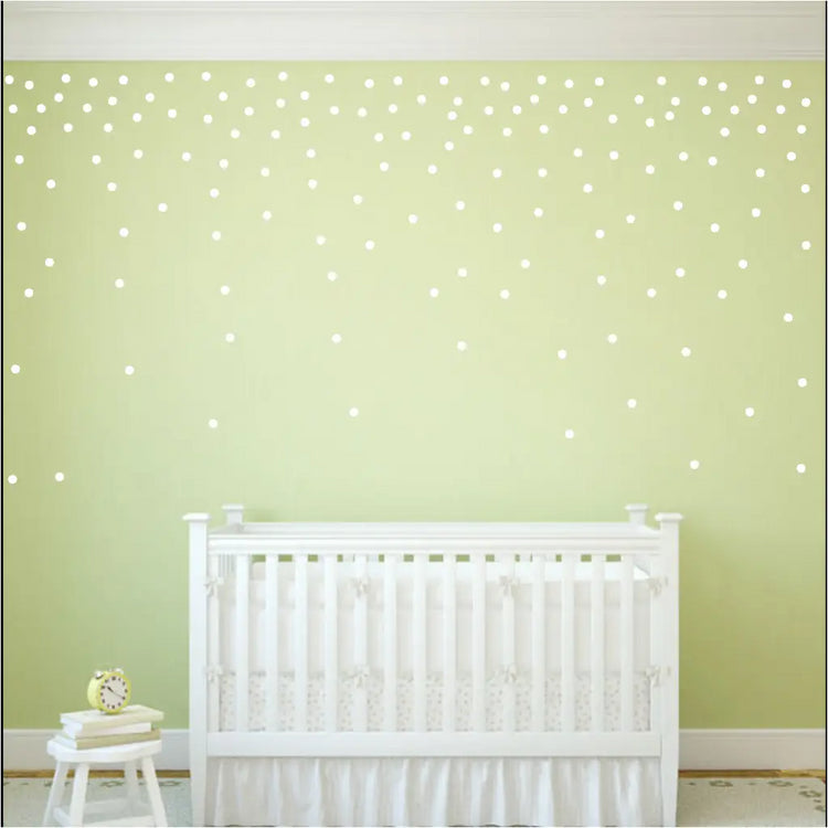 Peel and stick vinyl wall polka dots added to a baby's nursery wall creates a confetti pattern. Shown in white polka dots on green wall with a set of 112 - 1.5"  circles by The Simple Stencil