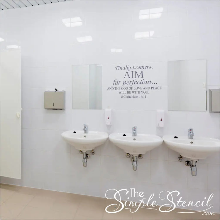 Inspirational scripture wall decal displayed on white tiles between bathroom mirrors as a reminder of faith in a public or office restroom.