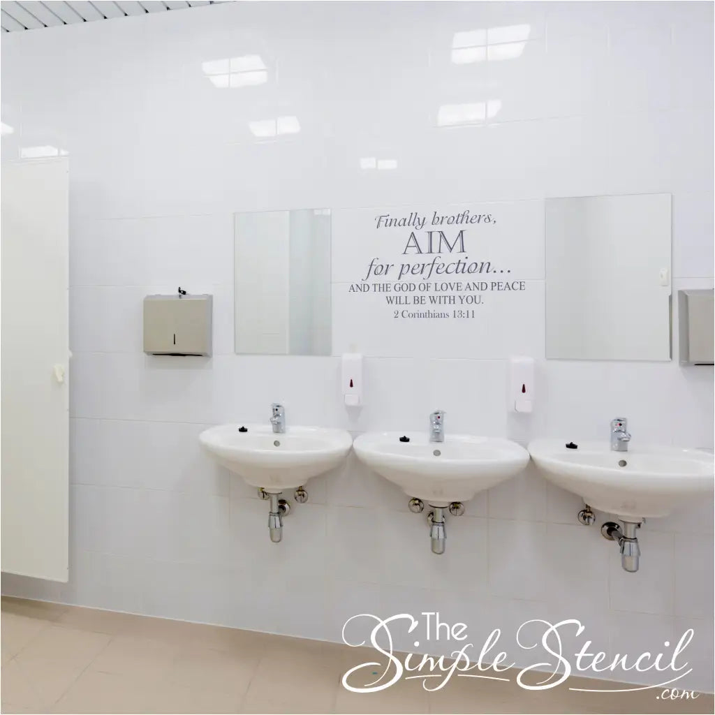 Inspirational scripture wall decal displayed on white tiles between bathroom mirrors as a reminder of faith in a public or office restroom.
