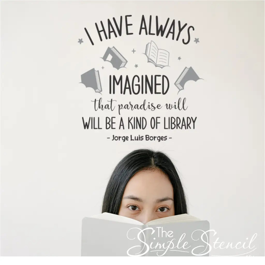 A person reading a book under the Borges quote wall decal with book, star, and cloud graphics.