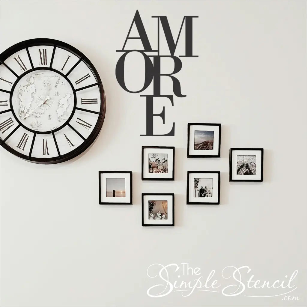 Matte Black  'AMORE' wall sticker incorporated into a living space gallery wall display, positioned next to a large round Roman numeral clock and six black-framed family photos.