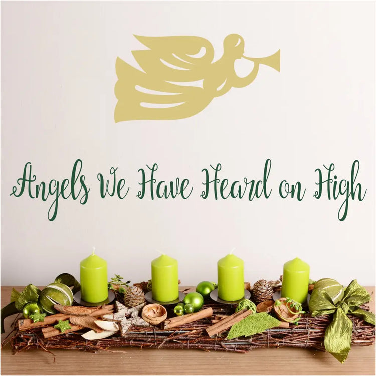 Angels we have heard on high - a pretty script wall decal displayed on a wall near christmas decor with a heralding angel graphic placed above by The Simple Stencil Christmas Decals