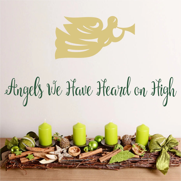 Angels we have heard on high - a pretty script wall decal displayed on a wall near christmas decor with a heralding angel graphic placed above by The Simple Stencil Christmas Decals