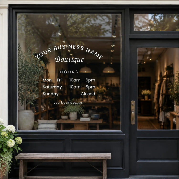 Arched business name and store hours vinyl decal in white on a boutique storefront window