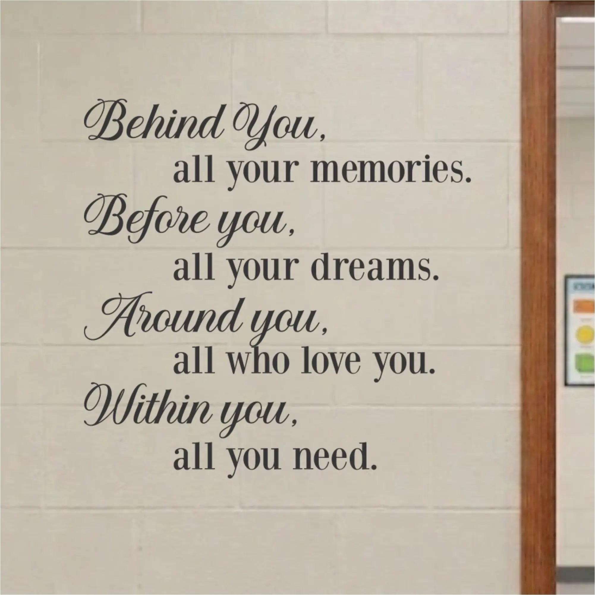 Black vinyl wall decal featuring a motivational quote, displayed on a light beige brick wall next to a wooden door frame.