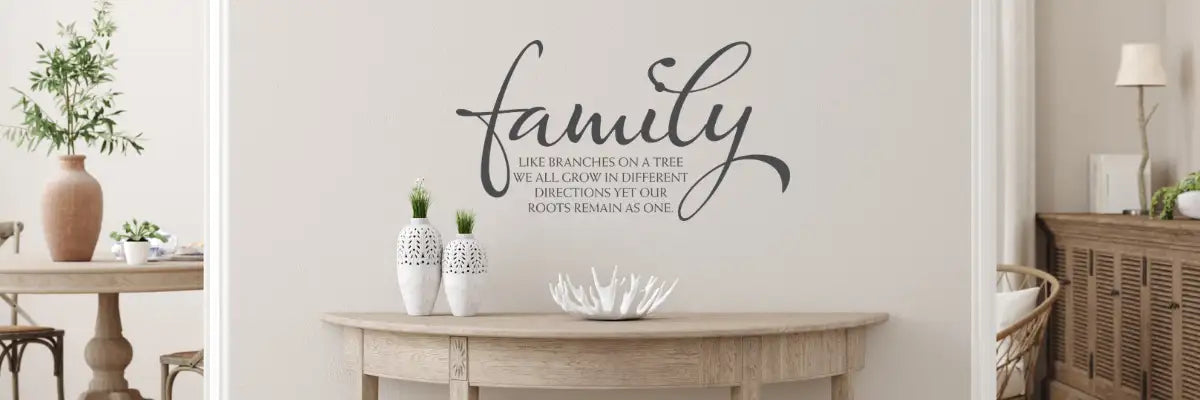 Black cursive ’family’ wall decal with inspirational quote beneath, mounted on a light-colored wall.