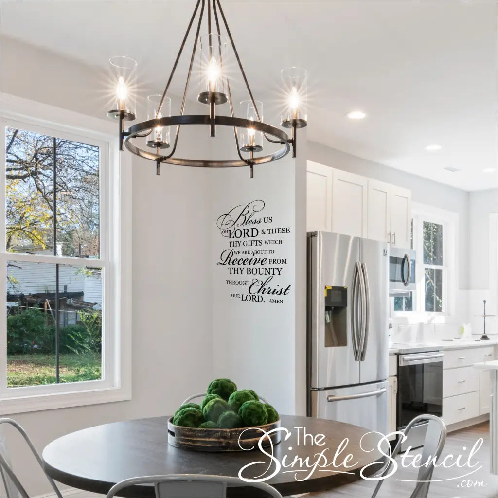 "Bless Us Oh Lord" wall decal in black vinyl on a white dining room wall.