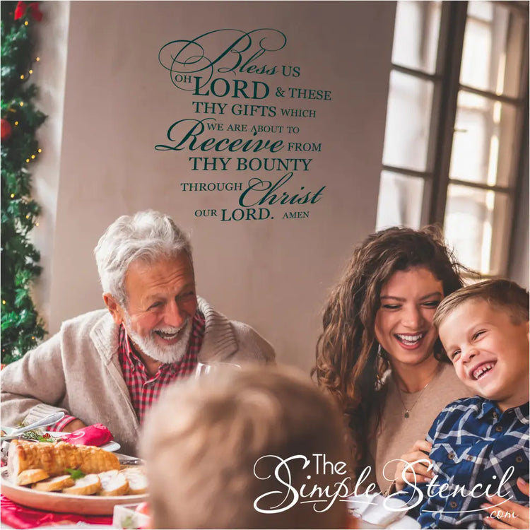 Family gathered around a dining table beneath a "Bless Us Oh Lord" wall decal by The Simple Stencil