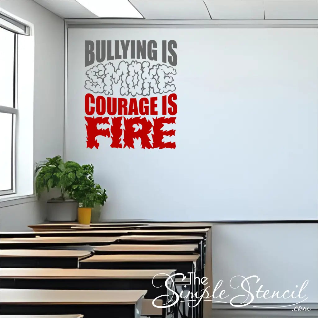 The "Bullying is Smoke, Courage is Fire" wall decal applied to a white wall at the front of a classroom, above several rows of empty wooden desks. A window is visible on the left, and a potted plant sits on a ledge near the desks.