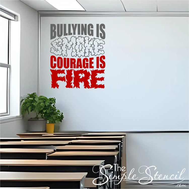 The "Bullying is Smoke, Courage is Fire" wall decal applied to a white wall at the front of a classroom, above several rows of empty wooden desks. A window is visible on the left, and a potted plant sits on a ledge near the desks.