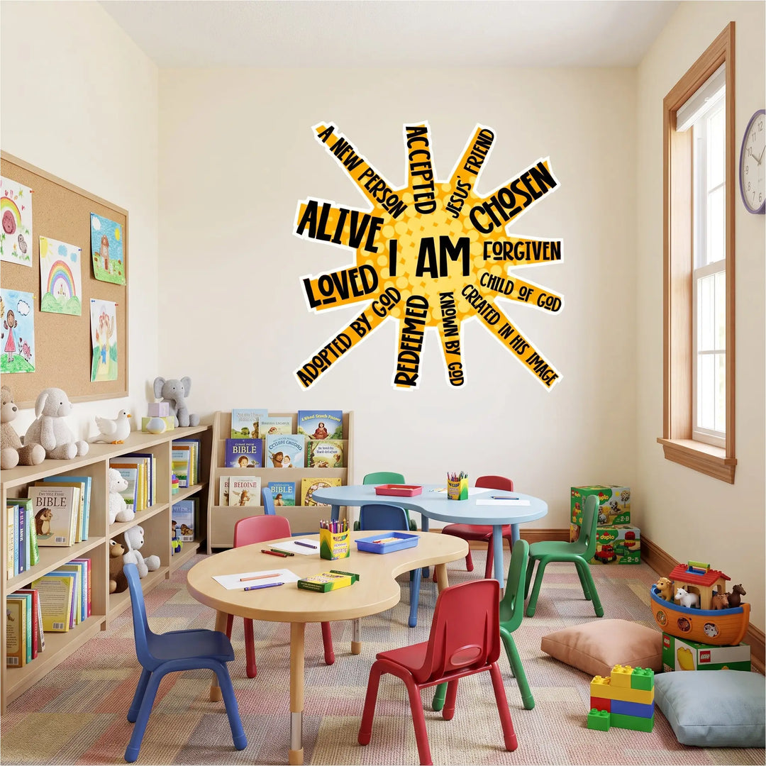 A church children's classroom or Sunday School room. The scene is viewed from a wide perspective, looking into a room with pale cream walls and a patterned carpet tile floor. Centered on the back wall is a large, yellow and black "I AM" sunburst wall decal with biblical phrases for kids. 