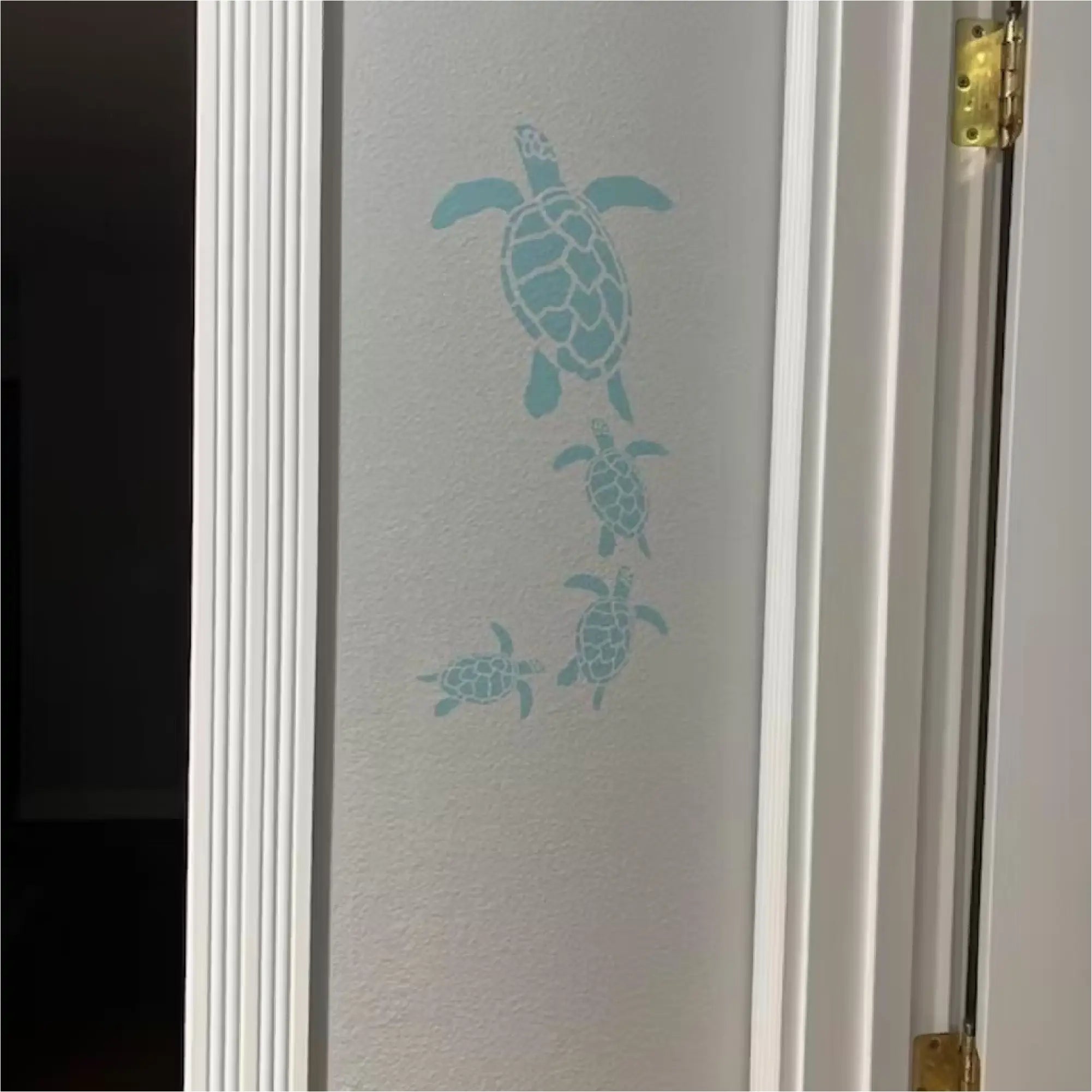 Coastal home decor: Self-adhesive wall art with a family of swimming sea turtles.