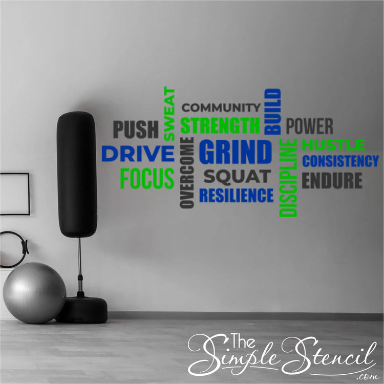 Blue, green, and dark grey gym word wall decal set displayed on a wall next to a freestanding punching bag and stability ball in a home fitness space.
