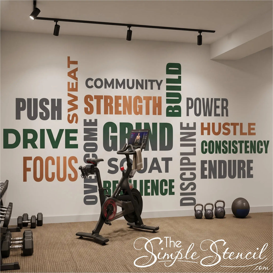 Motivational fitness word wall decal set in copper, forest green, and grey installed in a modern home gym behind a stationary workout bike.