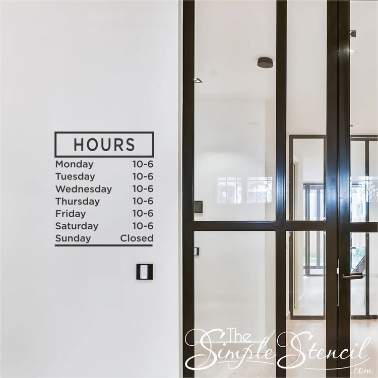 Custom business hours decal with a minimalist design and clear lettering on a retail store wall near the entrance.
