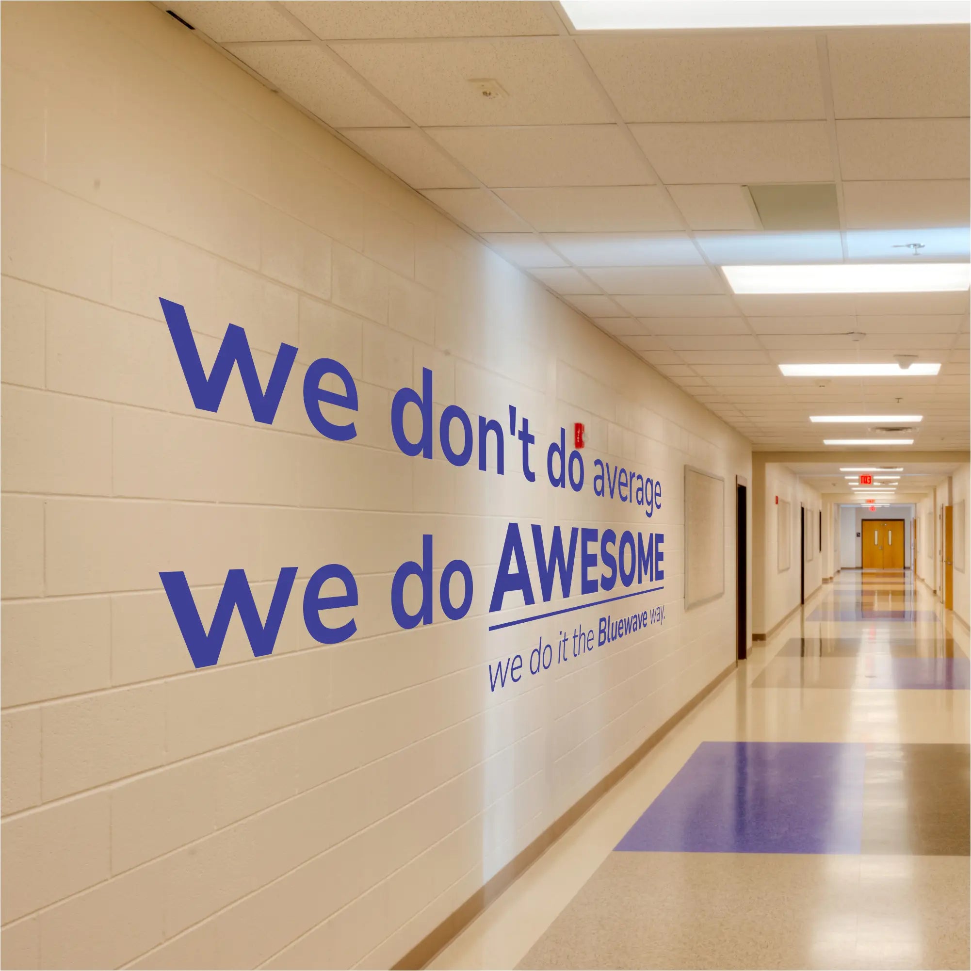 Large custom school wall decal reading "We Don't Do Average, We Do AWESOME The Bluewave WAY" in a modern, bold font on a bright school hallway wall, ideal for back-to-school decor.