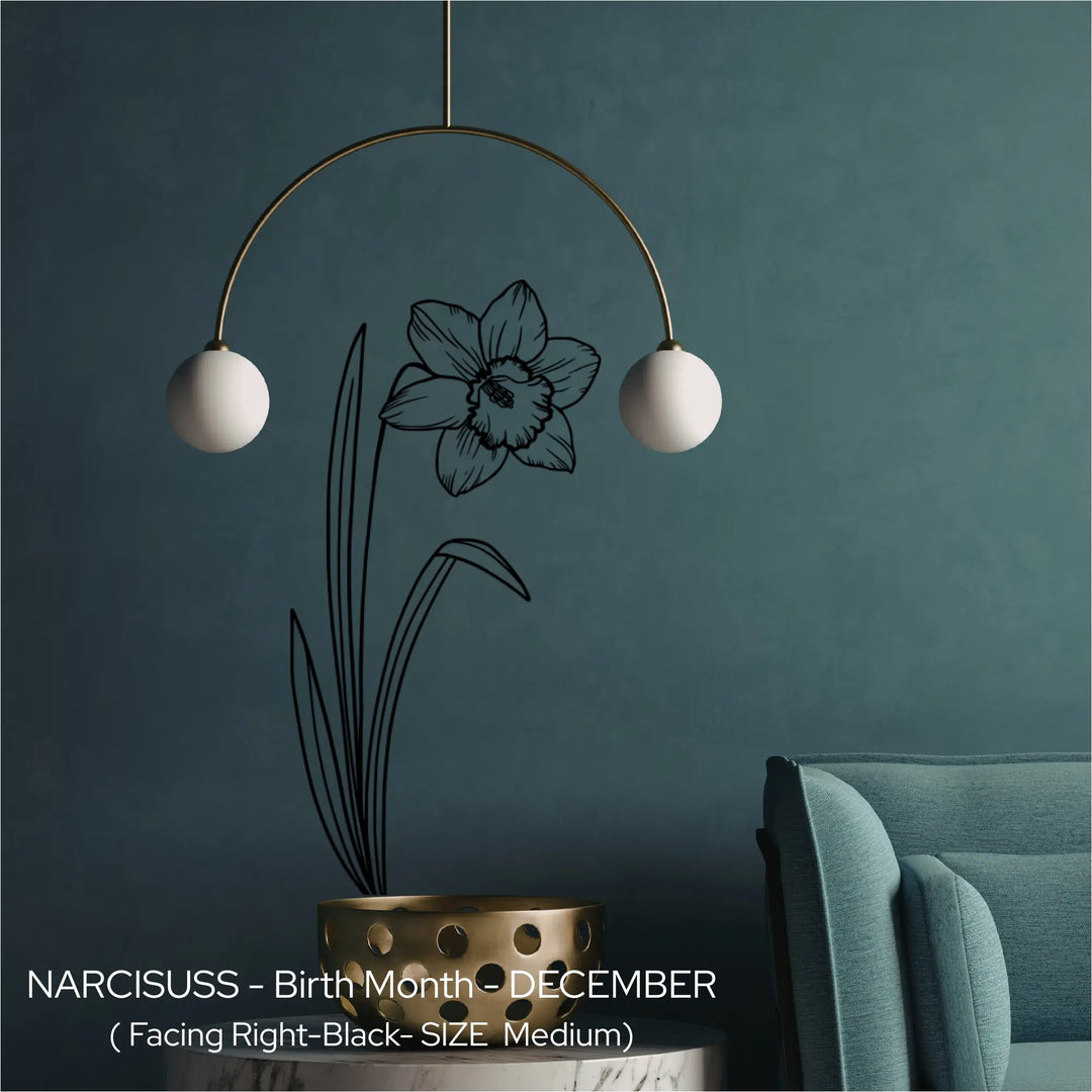 A black Narcissus birth flower wall etching applied vertically behind a modern mobile light fixture on a dark teal wall.