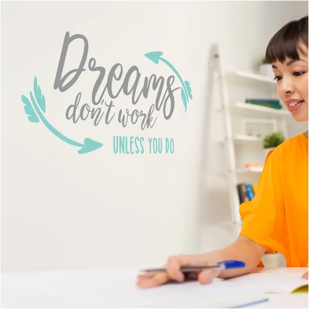 A cute wall decal in two colors displayed on an office wall that reads: Dreams don't work unless you do.