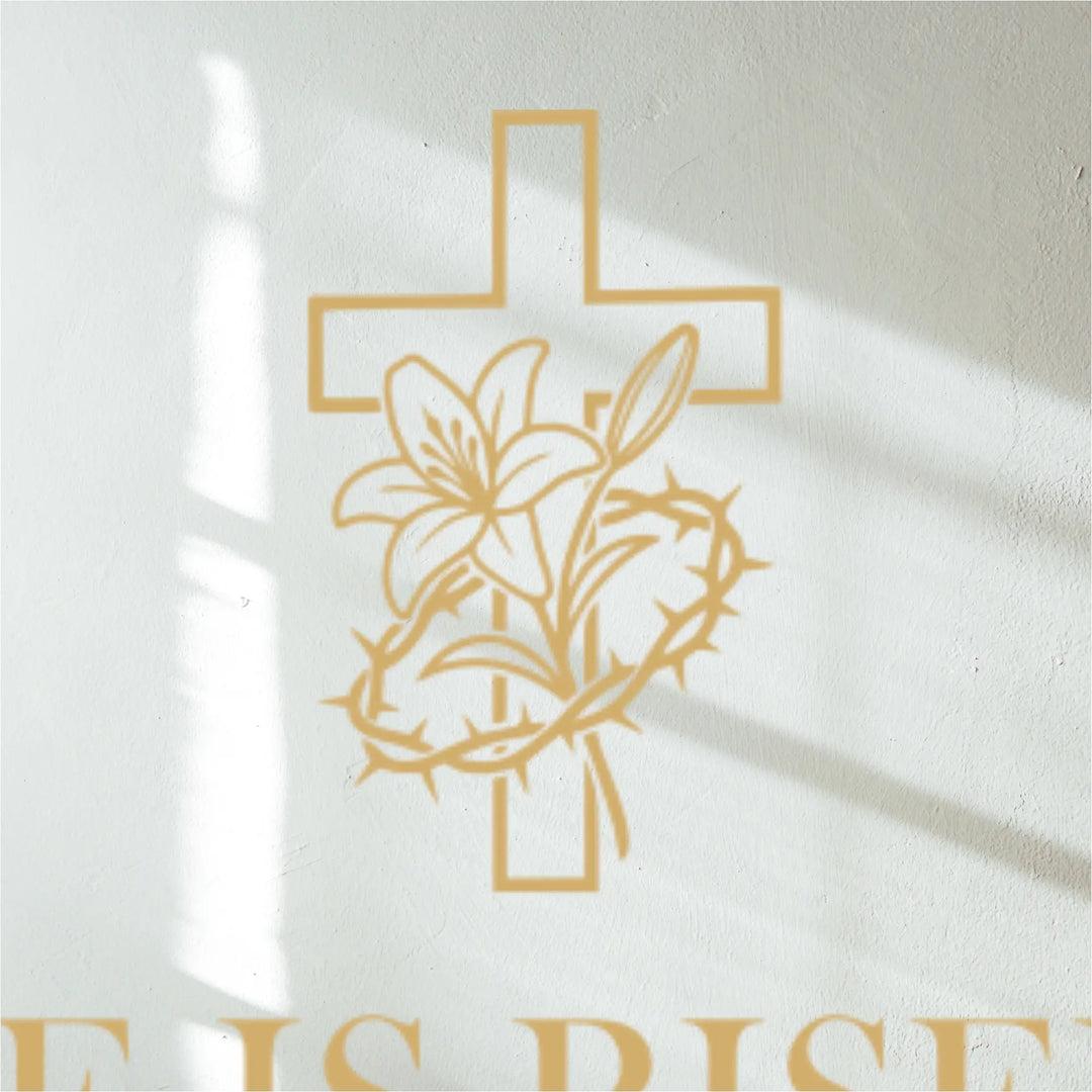 Gold cross with lily and thorns decal design on white wall above a decal  with 'He is Risen' text.